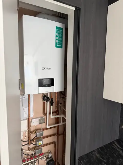 Vaillant combi boiler in a fitted kitchen cupboard with underfloor heating manifold